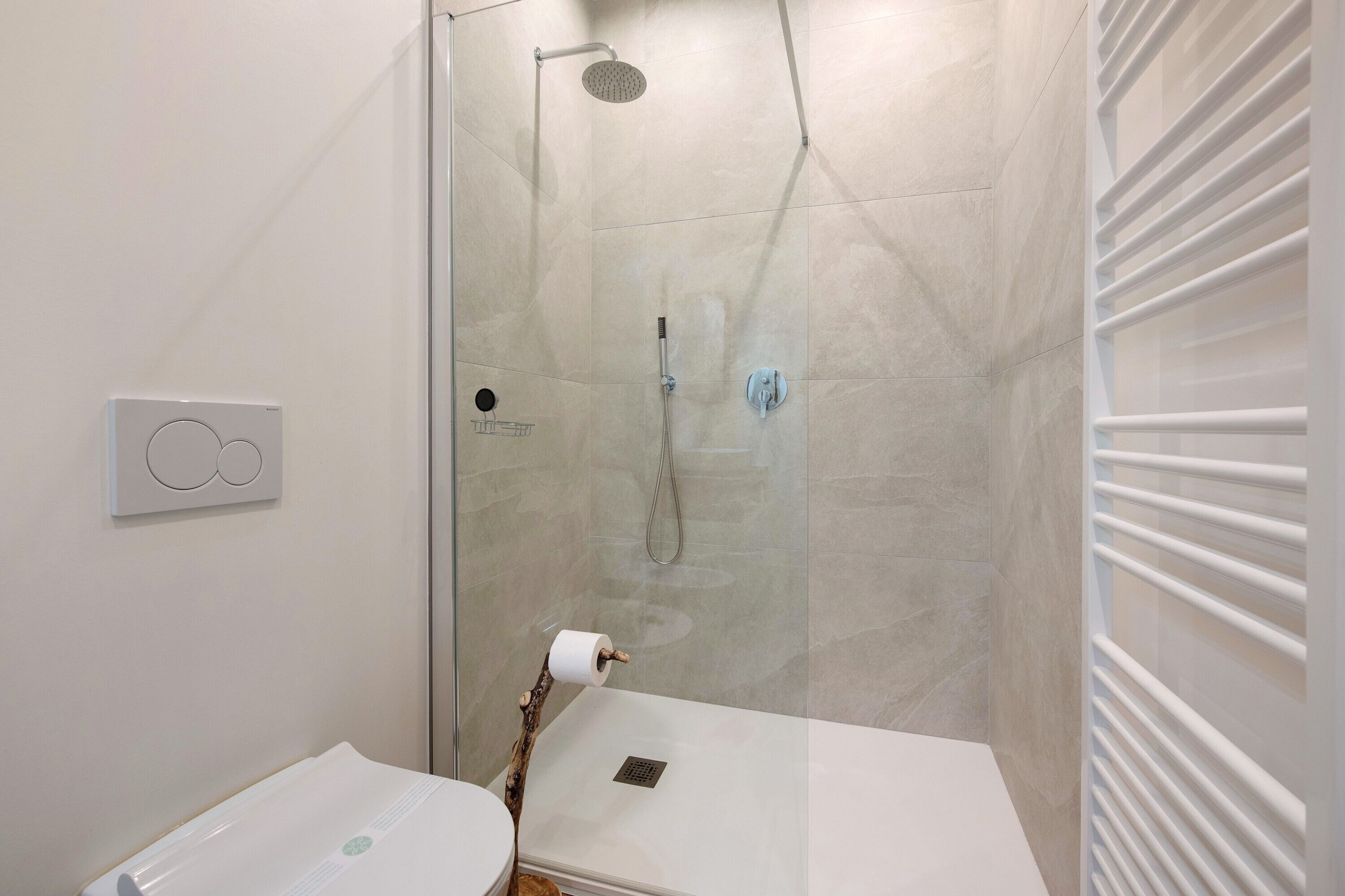 A modern bathroom with a glass-enclosed shower, a toilet, and a towel rack.