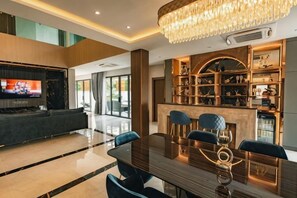 A modern interior with a dining area, a bar, and a television. - Astro Luxury: 4-6 beds Ultra Luxury Pool Villa with Daily Cleaning (Pattaya)