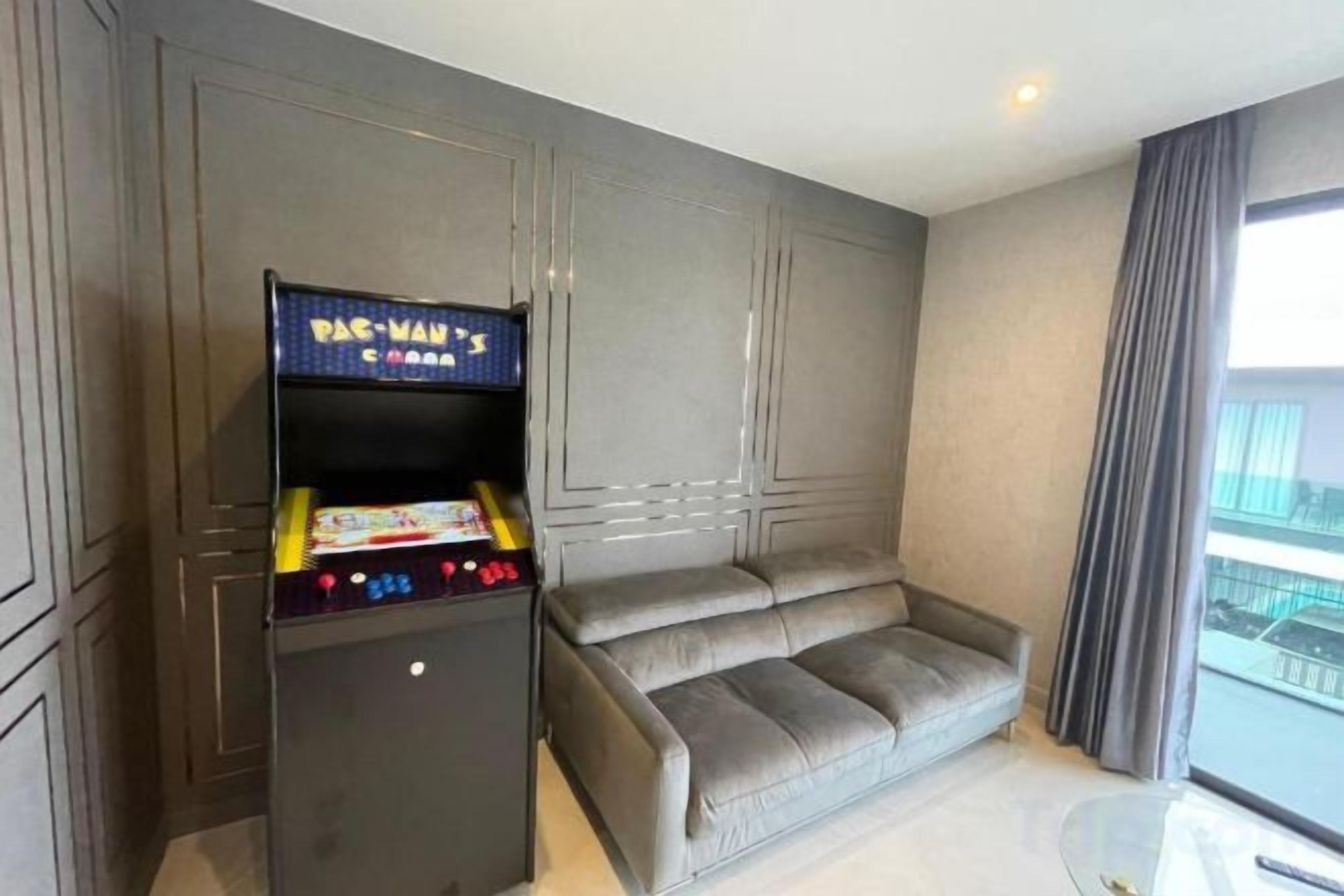 Una habitación con un sofá, una mesita y una máquina arcade de Pac-Man.