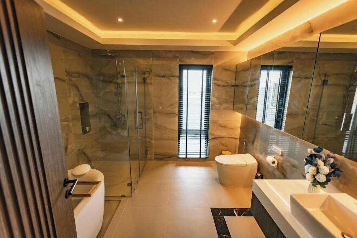 A modern bathroom with a glass shower enclosure, a large mirror, and a vanity with a sink.