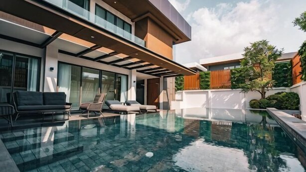 A modern house with a swimming pool, outdoor seating, and a large window overlooking the pool. - Astro Luxury: 4-6 beds Ultra Luxury Pool Villa with Daily Cleaning (Pattaya)