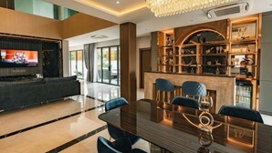 A modern interior with a dining area, a bar, and a television. - Astro Luxury: 4-6 beds Ultra Luxury Pool Villa with Daily Cleaning (Pattaya)
