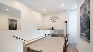 A modern kitchen with a dining table, chairs, a coffee machine, and a fire extinguisher.