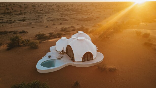 A desert landscape with a unique white dome-shaped building featuring a central pool and multiple rooms. - Reverie - Kalahari Pod (Mariental)
