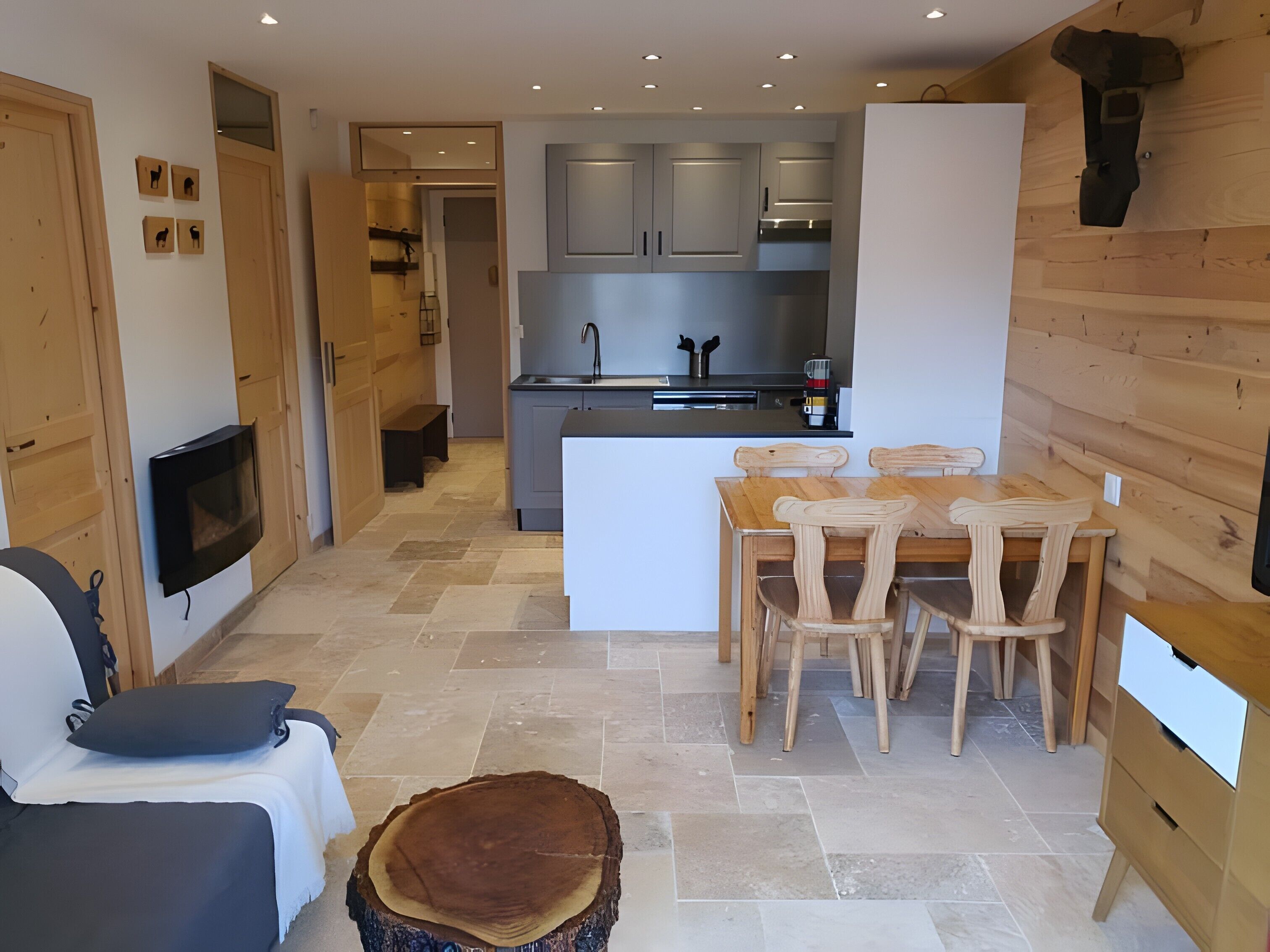 Une cuisine moderne avec des meubles gris, un îlot central et des chaises en bois.