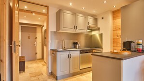 A modern kitchen with stainless steel appliances, wooden cabinets, and a countertop with a coffee maker. - Apartment 'Résidence 17' with Mountain View and Balcony (Les Deux Alpes)