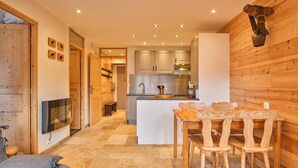 A modern kitchen with wooden cabinets, a central island, and a dining area with wooden chairs. - Apartment 'Résidence 17' with Mountain View and Balcony (Les Deux Alpes)