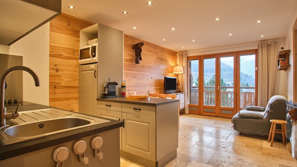 A kitchen with a sink, stove, and microwave, a dining area with a table and chairs, and a balcony with a view of the mountains. - Apartment 'Résidence 17' with Mountain View and Balcony (Les Deux Alpes)