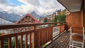 A balcony with wooden railings, a view of mountains, and a town below. - Apartment 'Résidence 17' with Mountain View and Balcony (Les Deux Alpes)