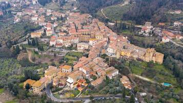 An aerial view of a historic town with closely packed buildings, winding roads, and surrounding greenery.