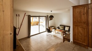 A spacious living area with a sliding glass door leading to an outdoor deck, a wooden cabinet, and a black chair.