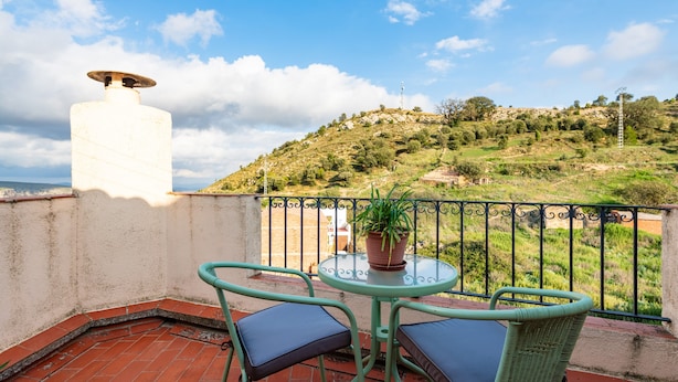 A terrace with a table and chairs, a potted plant, and a view of a hilly landscape. - Country House 'Casa Lino' with Mountain View, Private Terrace and Wi-Fi (Culla)