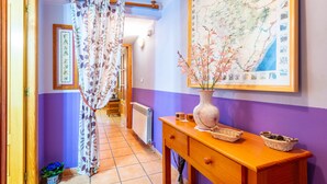 A hallway with a wooden door, a radiator, a map on the wall, a vase with flowers, and a wooden console table. - Country House 'Casa Lino' with Mountain View, Private Terrace and Wi-Fi (Culla)
