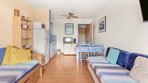 Un espacio habitable compacto con kitchenette, comedor y sofá.