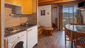 Una cocina con lavadora, techo de madera y comedor con mesa y sillas.
