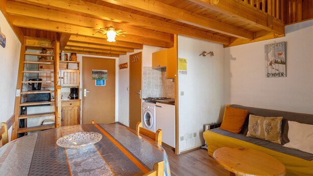 Un interior de madera con una mesa de comedor, un sofá, una lavadora y una zona de cocina.
