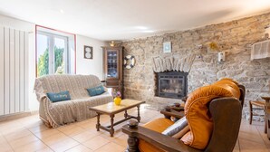 A cozy living room with a stone fireplace, a sofa, a chair, and a coffee table. - Holiday Home 800 m From the Beach with Private Terrace and Private Garden (Penmarc'h)
