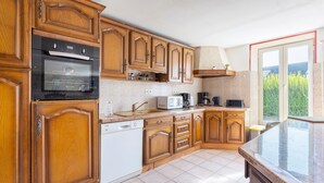 A kitchen with wooden cabinets, a built-in oven, a microwave, and a dishwasher. - Holiday Home 800 m From the Beach with Private Terrace and Private Garden (Penmarc'h)