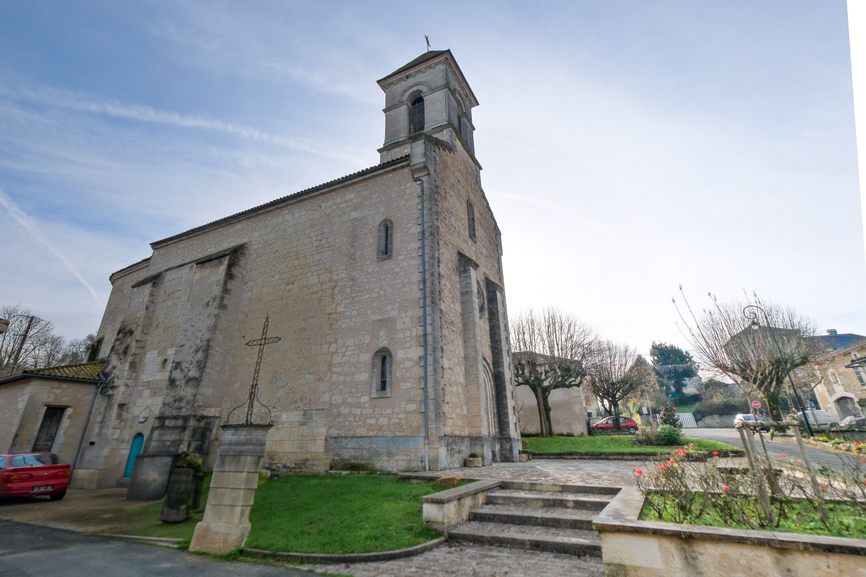 Eine Steinkirche mit einem Glockenturm, Stufen zum Eingang und einem kleinen Garten.