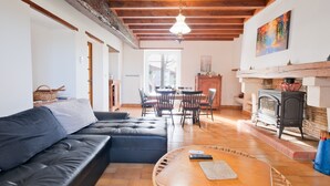 Una sala de estar con sofá, una mesa redonda, chimenea y un comedor con sillas.