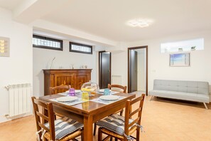 Un espace repas comprenant une table en bois, des chaises, un buffet et un canapé.
