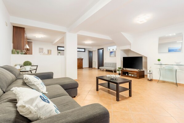Un salon moderne comprenant un canapé, une table basse, un téléviseur et un coin repas avec une table et des chaises.