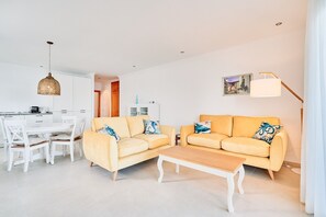 A modern living room with two yellow sofas, a wooden coffee table, a dining table with chairs, a hanging light fixture, and a floor lamp. - Apartment 'First Line Oasis  Td05' with Sea View, Wi-Fi and Air Conditioning (Torrox)
