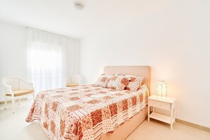 A bedroom with a bed, a nightstand, a chair, and a window with sheer curtains. - Apartment 'First Line Oasis  Td05' with Sea View, Wi-Fi and Air Conditioning (Torrox)