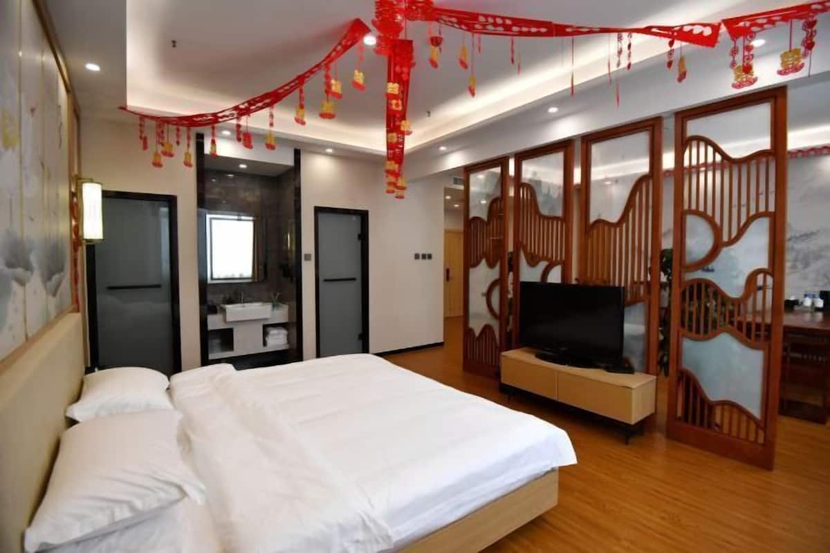 A hotel room with a bed, TV, wardrobe, and a bathroom.