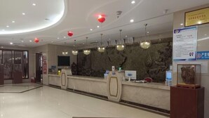 Ein Hotel-Empfangsbereich mit Marmor-Theke, roten Laternen und einer Wand mit Steinoptik.