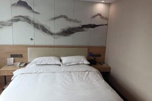 A hotel room with a bed, a nightstand with a phone, and a wall with a decorative panel.