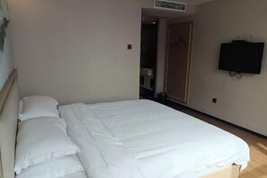 A bedroom with a bed, a television mounted on the wall, and a door leading to another room.