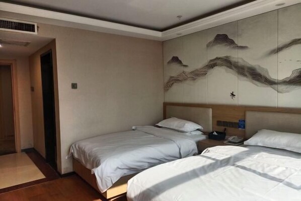 A hotel room with two beds, a large wall mural, and a wooden headboard.