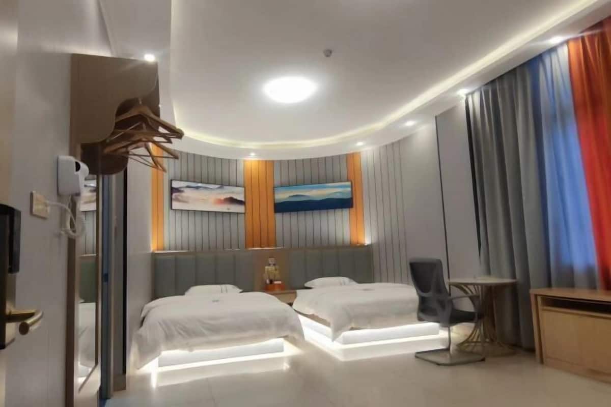 Ein modernes Hotelzimmer mit zwei Betten, einem Schreibtisch, einem Stuhl und einem kleinen Tisch.