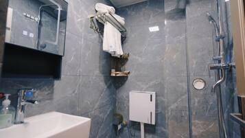 A bathroom with a sink, mirror, towel rack, and shower.