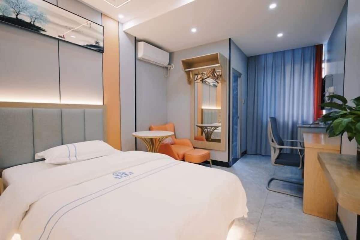 Ein Hotelzimmer mit Bett, Schreibtisch, Stuhl, einem kleinen Tisch und einem Spiegel.