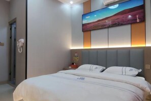 Une chambre d’hôtel avec un lit, un tableau au mur et un téléphone fixé au mur.