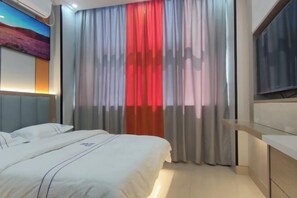Une chambre d’hôtel avec un lit, une télévision et un tableau au mur.