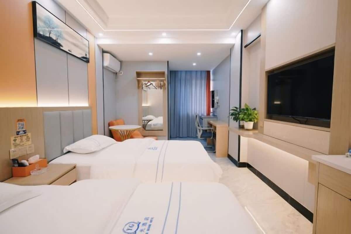 Ein Hotelzimmer mit zwei Betten, einem Schreibtisch, einem Fernseher und einem Badezimmer.