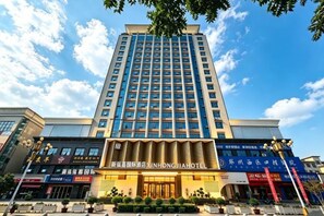 Un hôtel à plusieurs étages, doté d’une entrée imposante et d’une enseigne bien visible indiquant « XINHONGJIA HOTEL ».