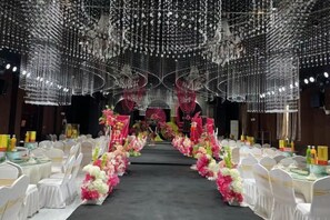 Un salón de banquetes con sillas y mesas blancas, y centros de mesa con flores.
