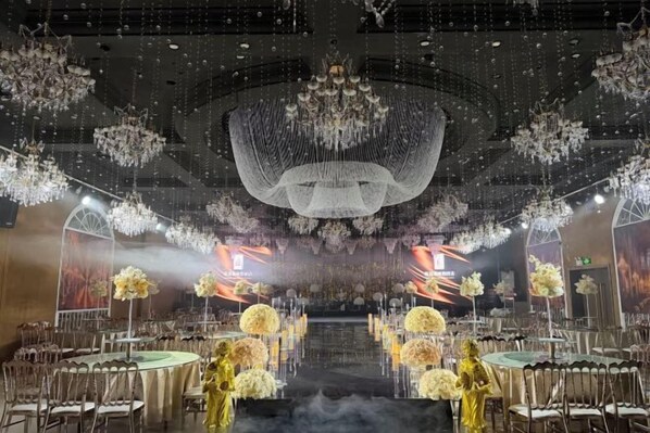 Un salón de banquetes con mesas redondas, candelabros y centros de mesa florales.
