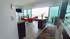 Una cocina moderna con comedor, ventanas amplias y vista al océano.