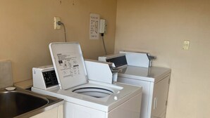 A laundry area with a washing machine and dryer, a sink, and a sign indicating guest laundry closure times. - Hawker Hotel Motel (Hawker)