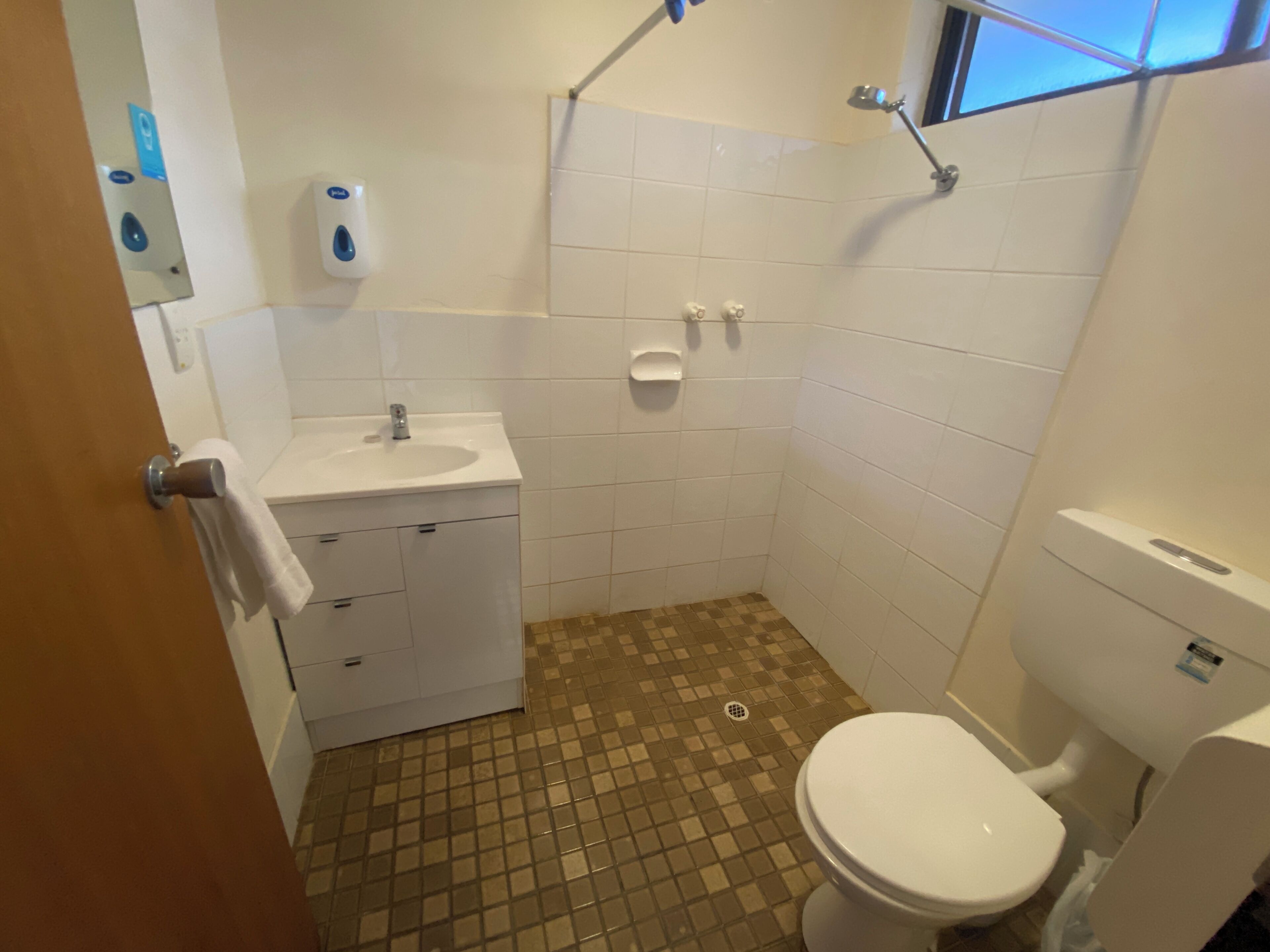 A small bathroom with a white sink, a toilet, and a shower area.