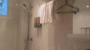 A bathroom with a shower, a toilet, and a towel rack.