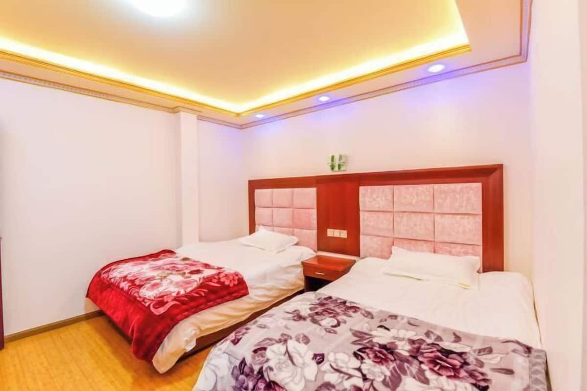 Ein Hotelzimmer mit zwei Betten, einem hölzernen Kopfteil und einer Deckenleuchte.