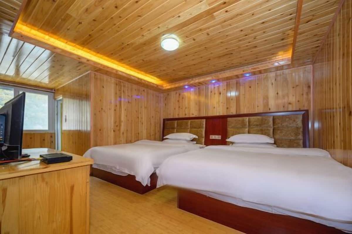 Ein Zimmer mit Holzwänden, zwei Betten, einem Schreibtisch mit Computer und einem Fernseher.