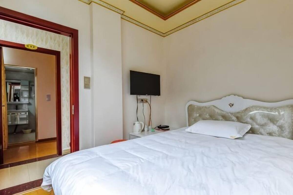 Ein Hotelzimmer mit Bett, Fernseher und einem durchgegangenen Tür sichtbaren Badezimmer.