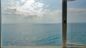 Vista a través de una ventana con cielo despejado y mar tranquilo.